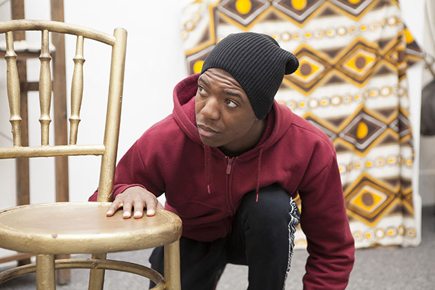 Actor Isaiah Bobb-Semple in rehearsal, crouching down by a chair