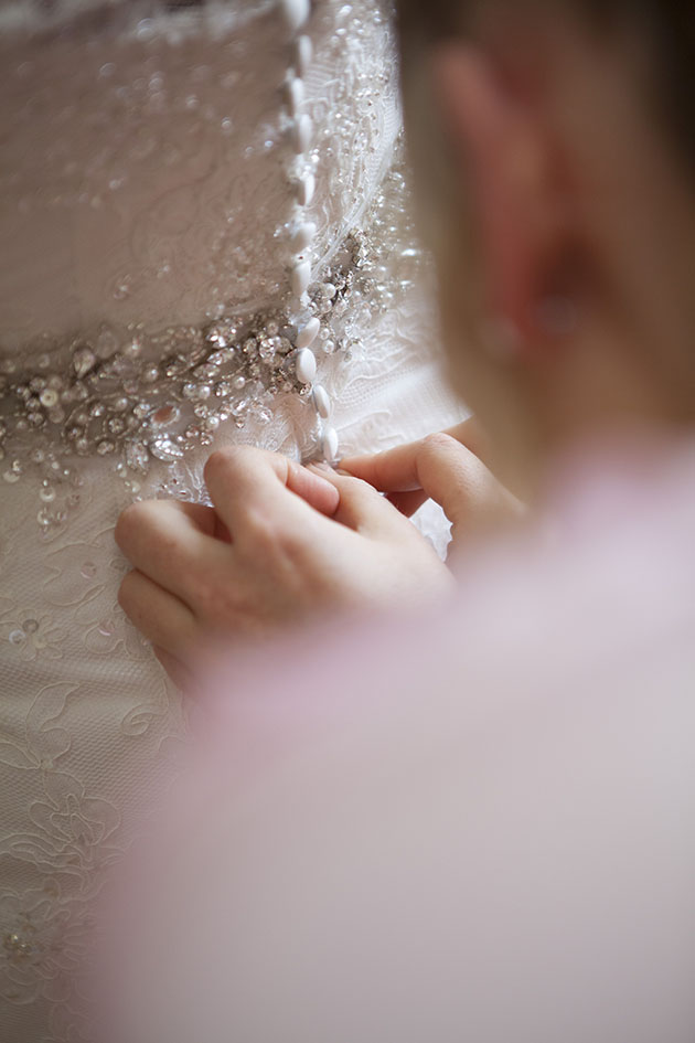 close up detail of back of wedding dress buttons being done up