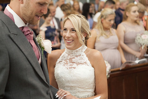 bride smiling at groom and holding his arm during the wedding ceremony