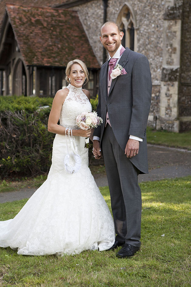 full length portrait of bride and groom in grounds of Essex church