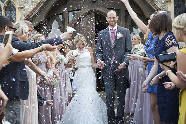 bride and groom walking down an avenue of people throwing confetti