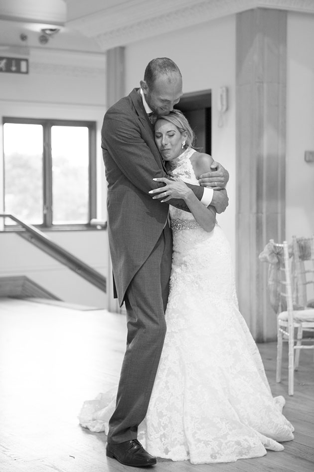 full length portrait of groom with arms around his emotional bride