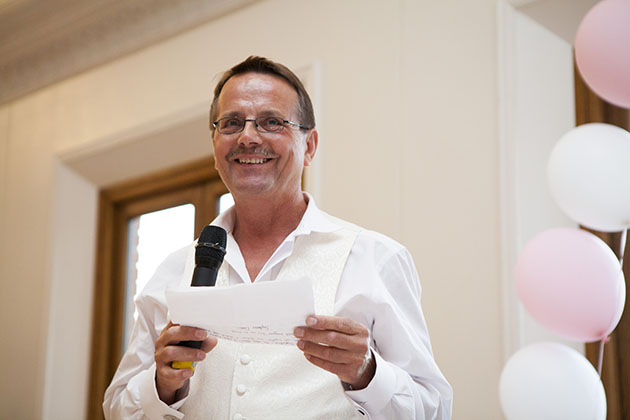 father of the bride holding a microphone during the wedding speeches