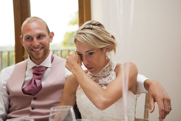 bride wiping a tear during the wedding speeches