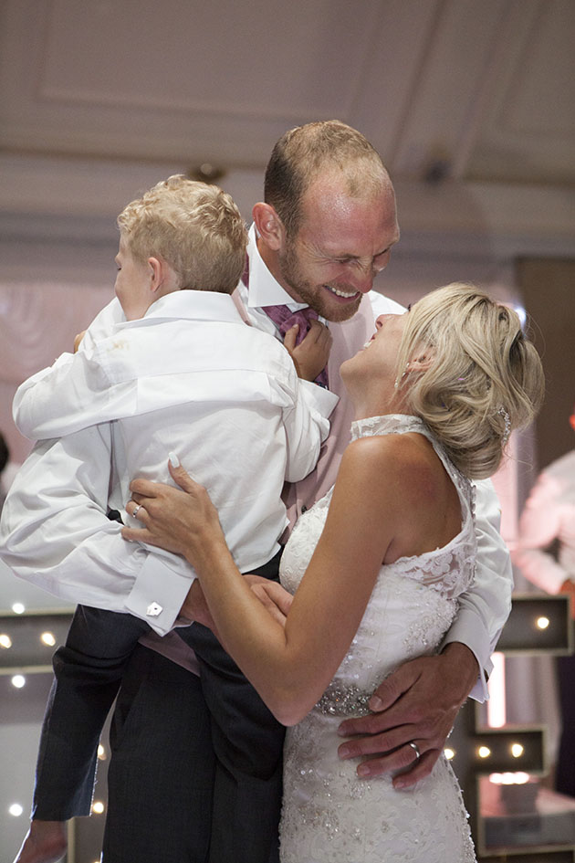 bride and groom holding their young son and all laughing