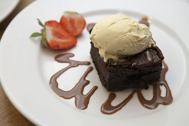 Chocolate brownie with ice cream and a strawberry on a plate