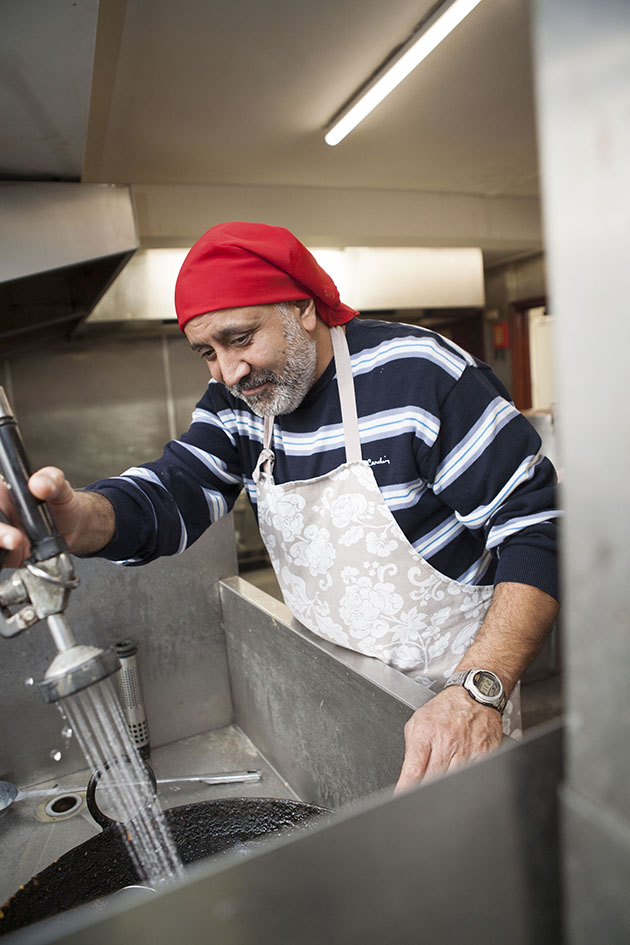 Indian man washing dishes in large kitchen