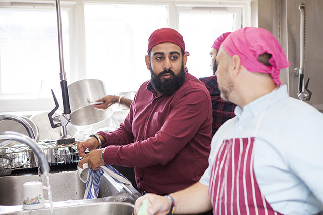 Men washing dishes in large kitchen