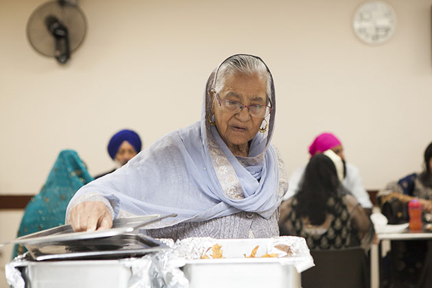 Woman serving herself food at a Sikh kitchen