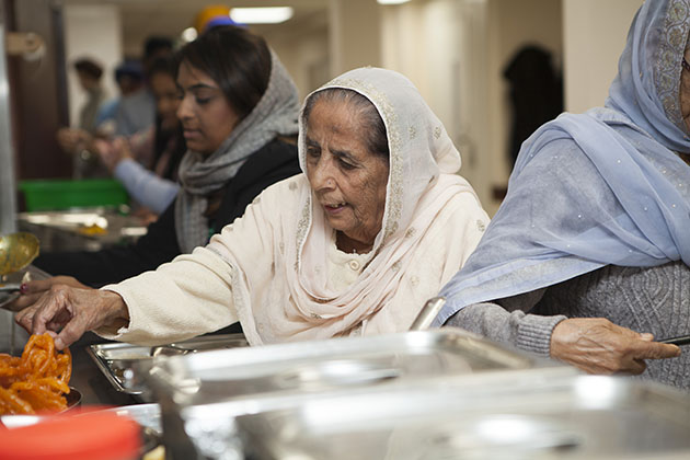 Woman serving herself food at a Sikh kitchen
