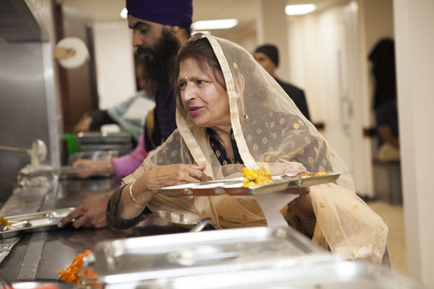 Woman serving herself food at a Sikh kitchen