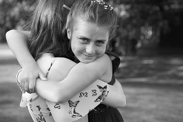 Young bridesmaid hugging an older girl and looking at camera