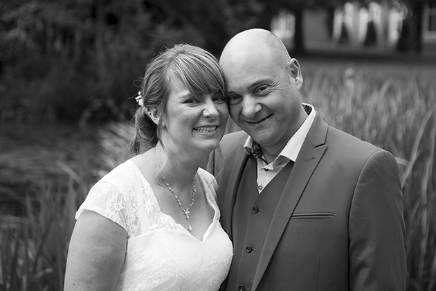 Black and white portrait of bride and groom with pond on the background