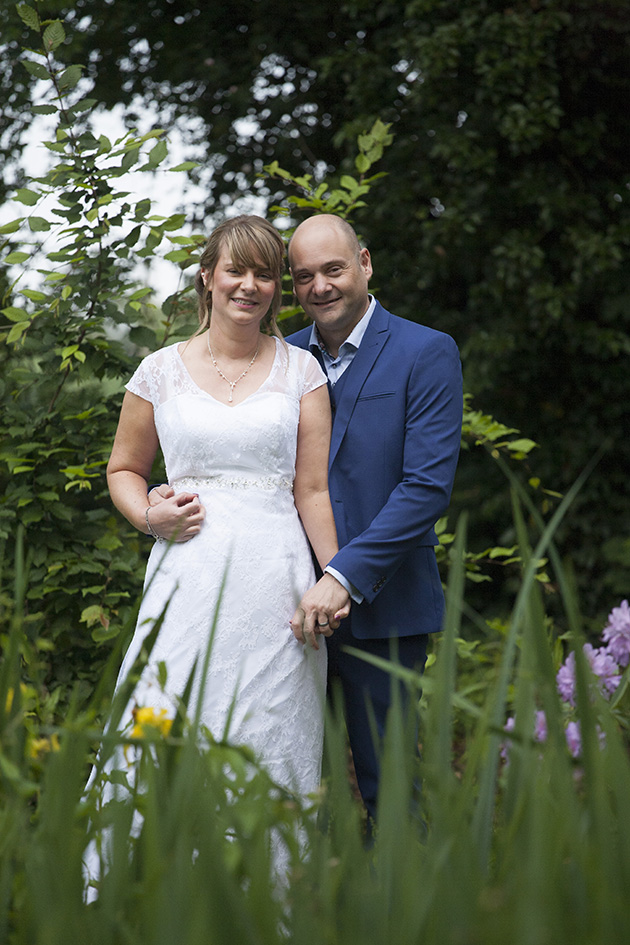 Natural portrait of bride and groom standing in tall grass