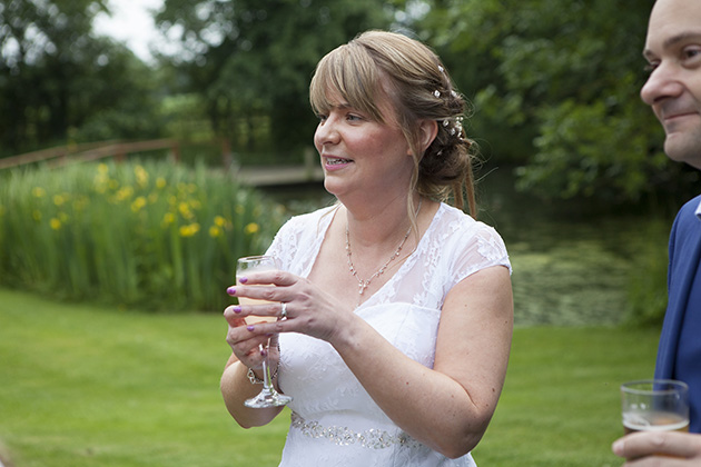 Candid photo of bride in garden holding champagne glass