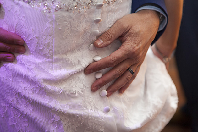 Close-up of groom's hands around the bride's waist during first dance at wedding