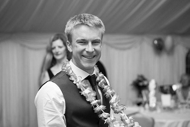 Black and white portrait of wedding guest looking at camera and laughing