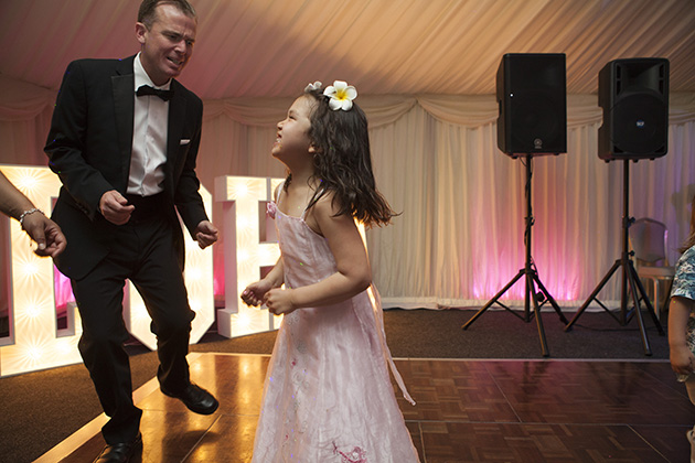 Young girl dancing with man wearing black tie at a wedding 