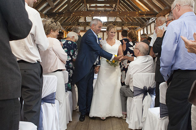 Groom stopping to shake hands with the bride's father as they walk back up the aisle