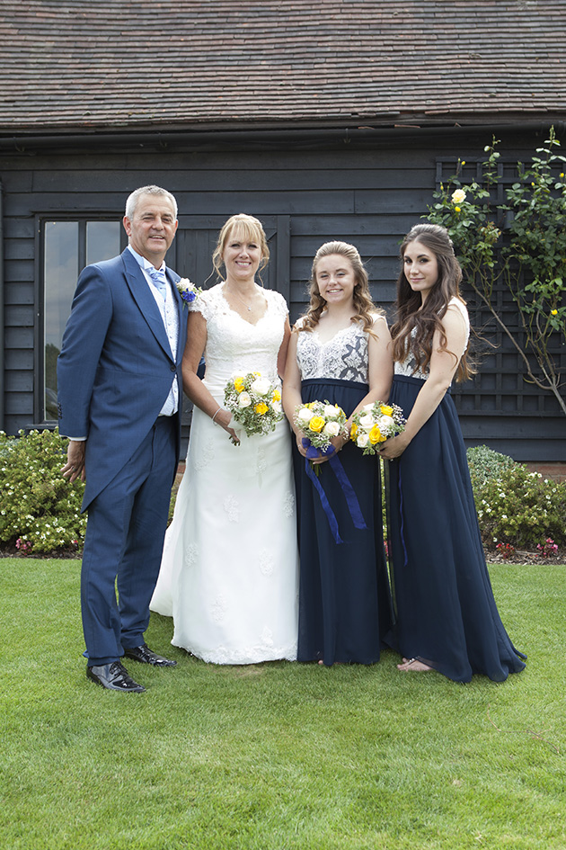 Small wedding group photo on grass outside barn