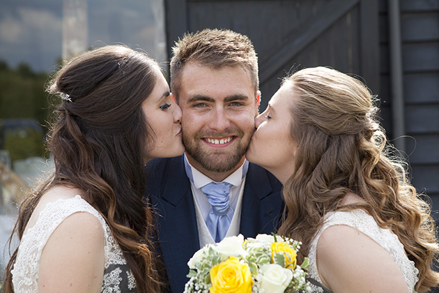 Bridesmaid sisters both kissing their brother on the cheek