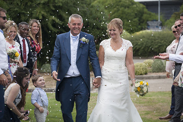 Bride and groom walking between lines of people throwing confetti