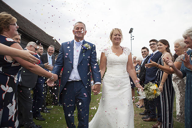 Bride and groom walking between lines of people throwing confetti