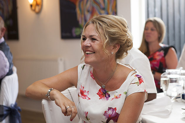 Seated wedding guest with arm on back chair listening to speeches