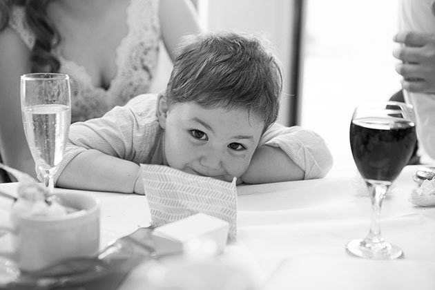 Cheeky toddler leaning on table and looking at camera