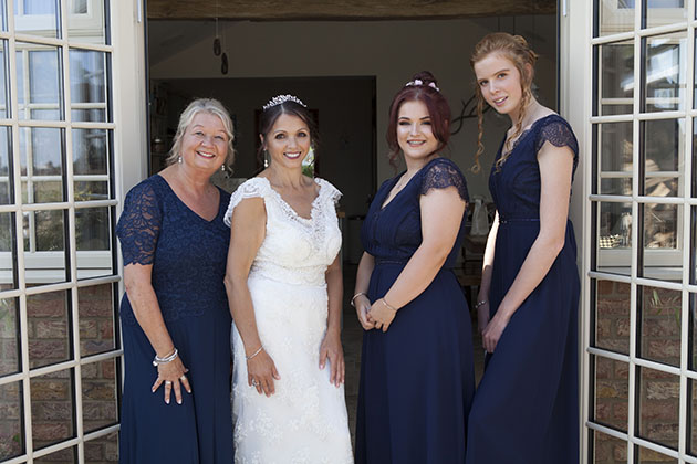 Bride and three bridesmaids standing by patio doors