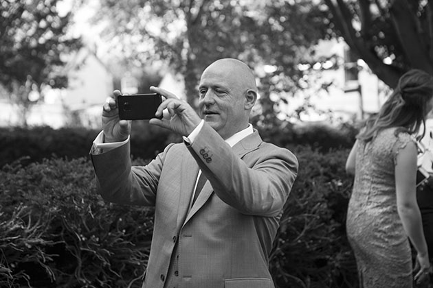 Groom taking a photo outside church