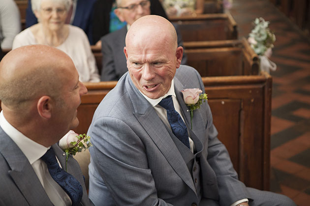 Candid photo of best man in church talking to the groom
