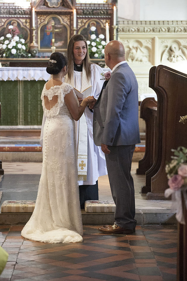 Wedding ceremony showing the bride, groom and vicar photographed from end of the church aisle