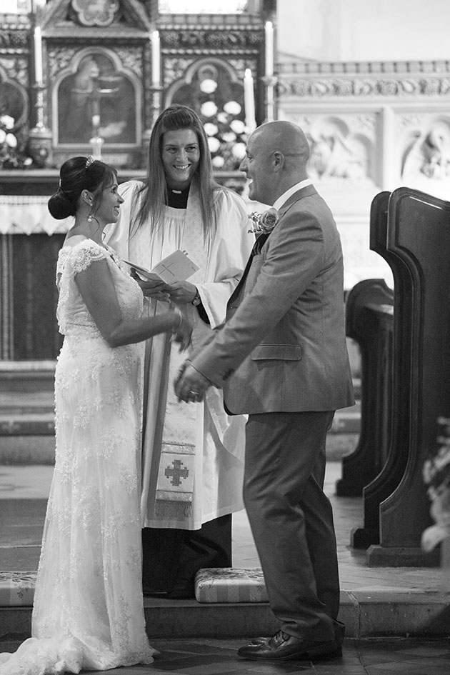 Wedding ceremony showing the bride, groom and vicar photographed from end of the church aisle