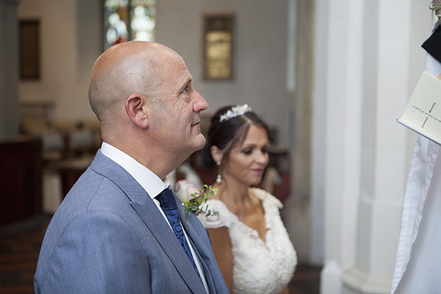 Groom kneeling before vicar during wedding ceremony