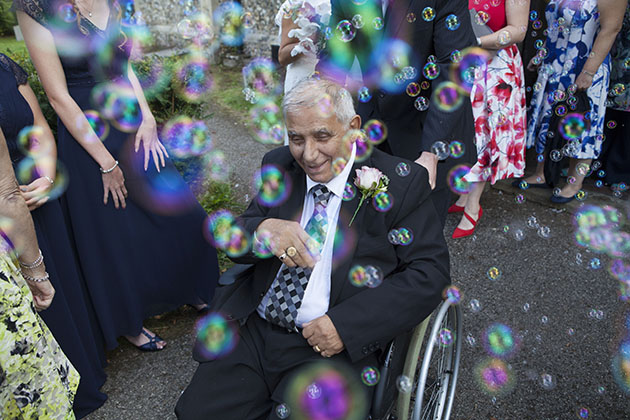Man in wheelchair surrounded by wedding guests and bubbles