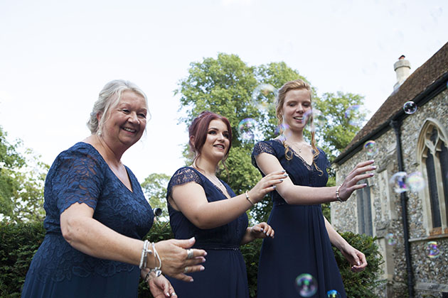 Three bridesmaids catching bubbles