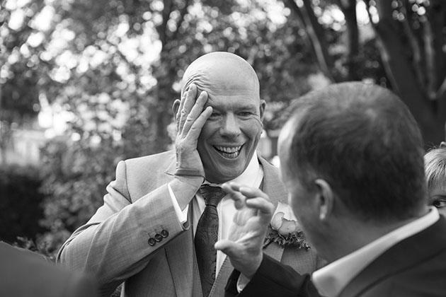 Best man at wedding touching his head and laughing