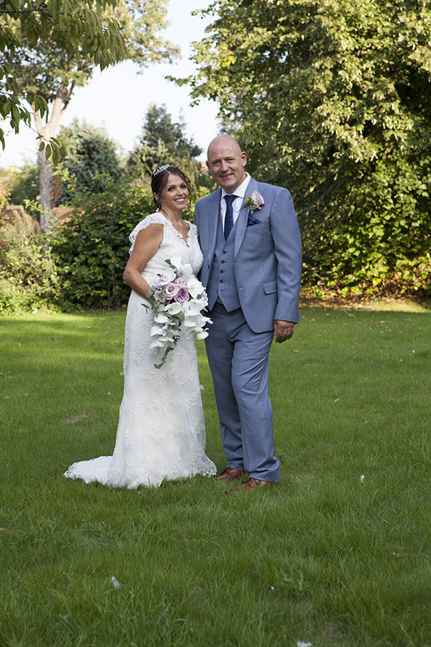 Full length portrait of bride and groom in church garden