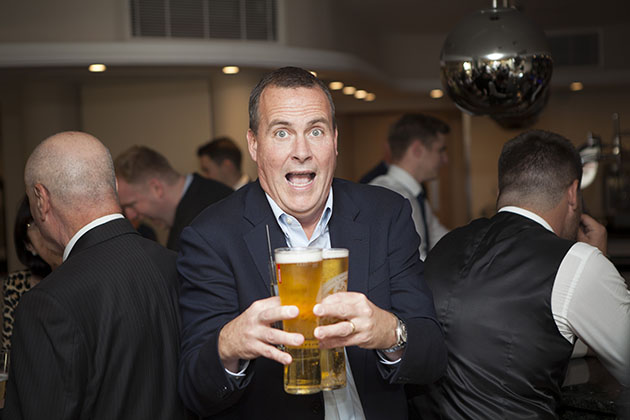 Man holding three pints of lager and walking towards camera