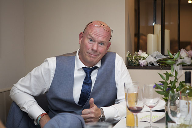 Wedding guest at table looking at camera and making a thumbs up sign