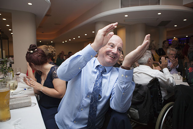 Reportage image of wedding guest leaning and clapping