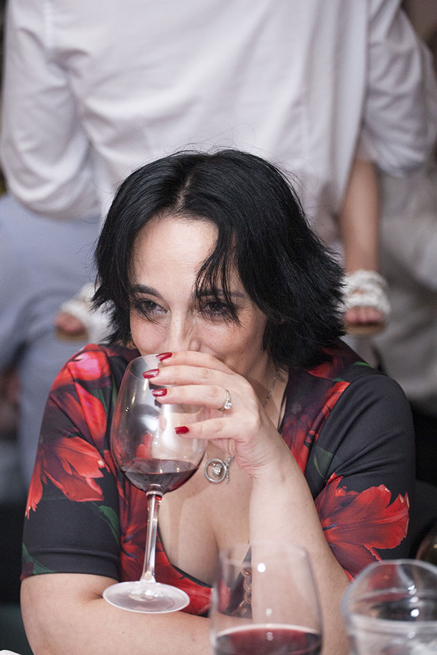 Candid portrait of woman in red dress drinking wine