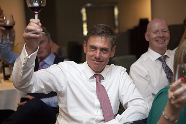 Wedding guest raising wine glass and looking at camera