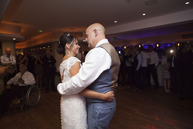 bride and groom's first dance with guests in the background