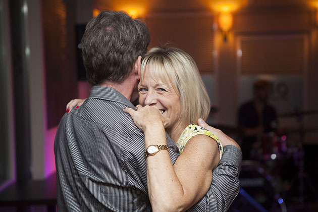 Woman dancing with her hands around her partners shoulders and looking at camera