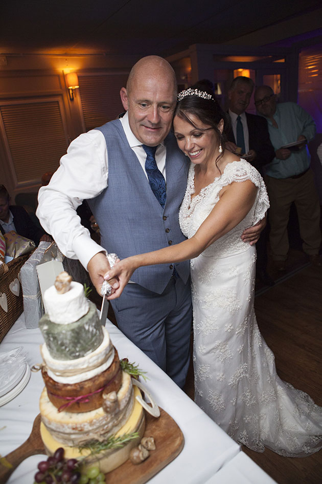 Married couple cutting wedding cake made of cheese