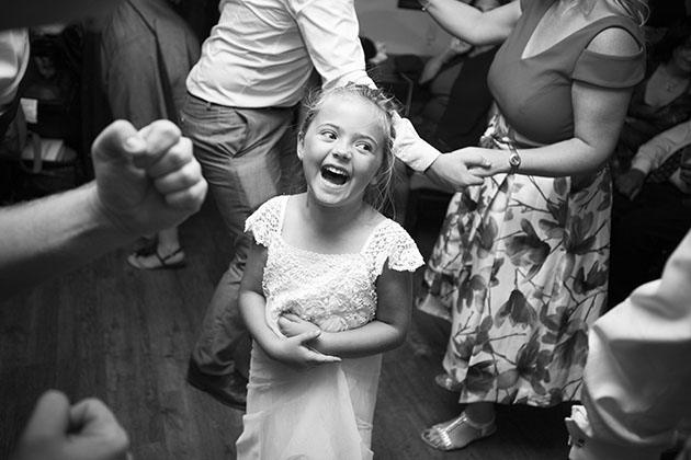 Young child laughing on dance floor surrounded by wedding guests