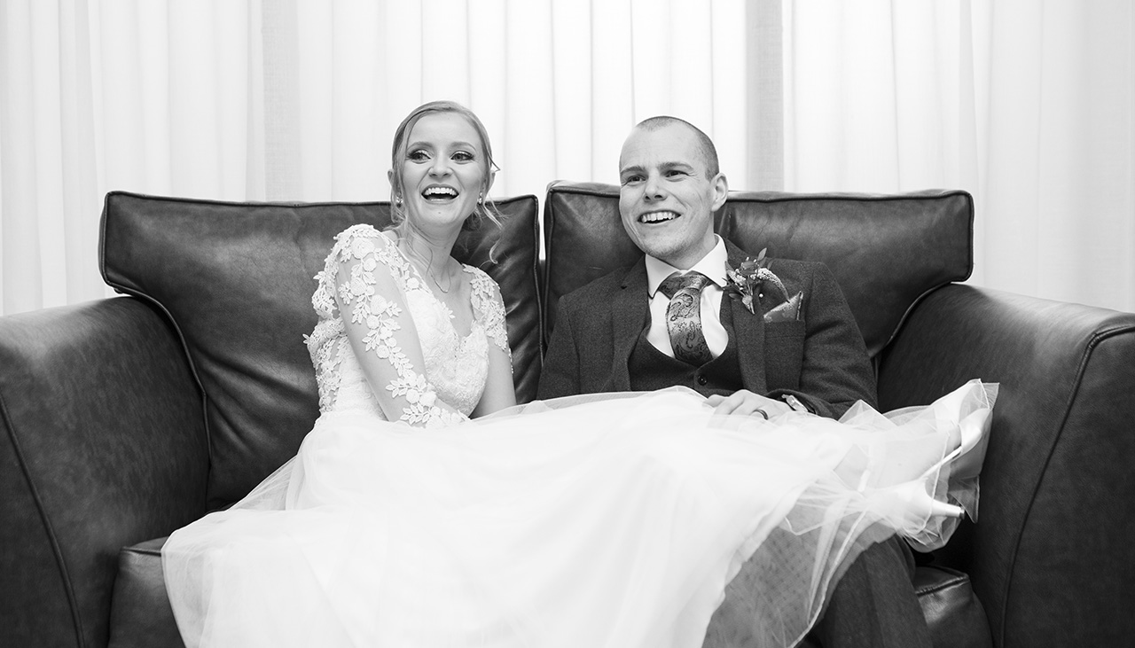 Bride and groom sitting on a sofa in The Essex Barn at Channels Estate